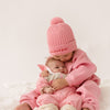 Cinnamon baby pom pom beanie in fairy floss pink, soft and cozy toddler hat with playful pom pom for cooler days.