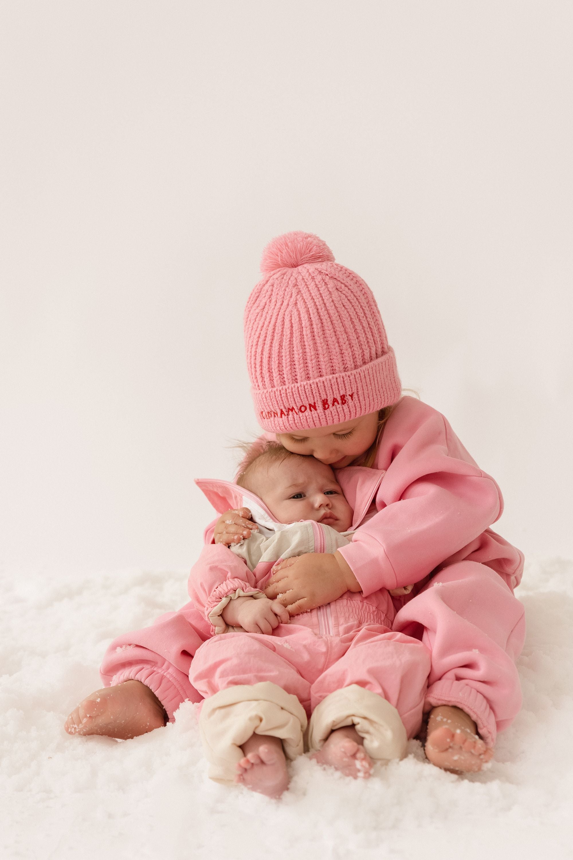 Cinnamon baby pom pom beanie in fairy floss pink, soft and cozy toddler hat with playful pom pom for cooler days.